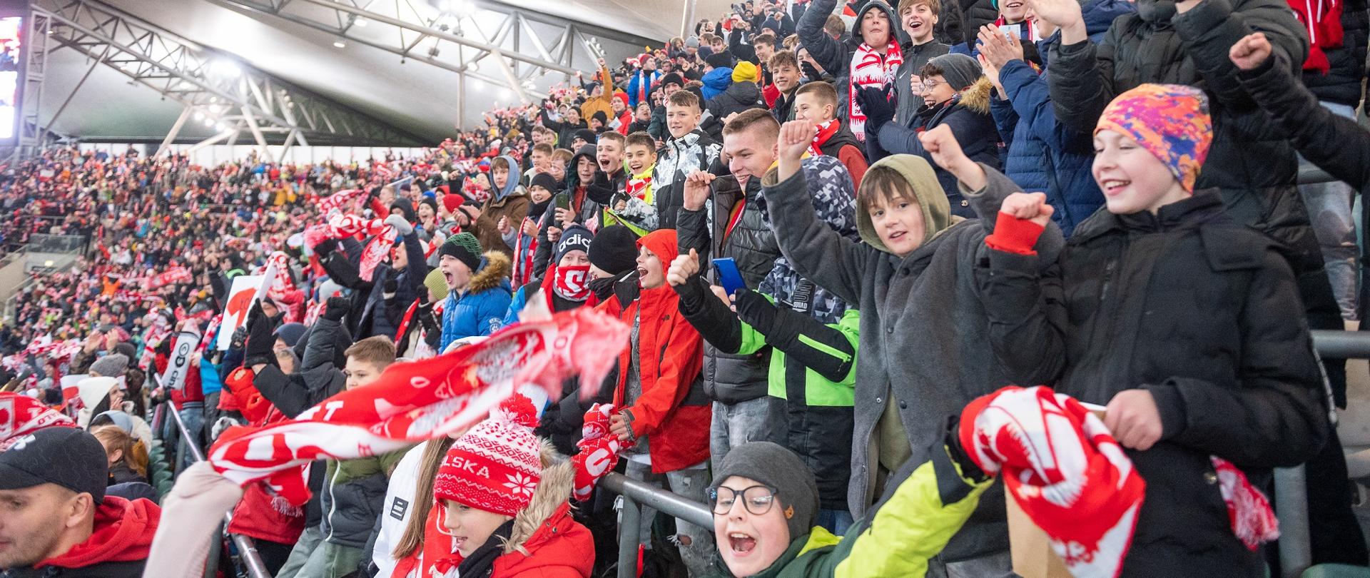 Widok z boku na wypełnione ludźmi trybuny stadionu.