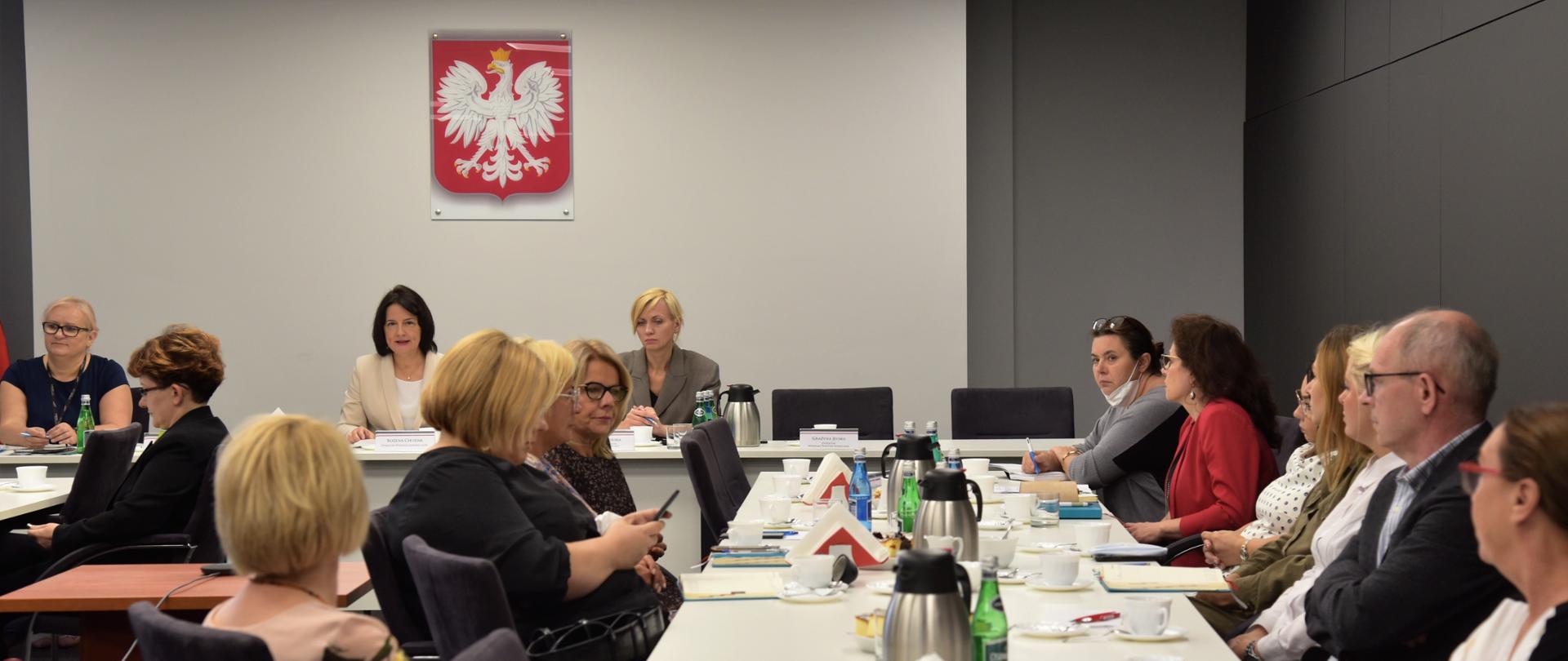 Widok z końca sali na obradujących uczestników spotkania dotyczącego opieki długoterminowej, geriatrycznej, paliatywnej i hospicyjnej.