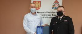 Zdjęcie przedstawia komendanta powiatowego PSP w Kwidzynie mł. bryg. Wojciecha Berent wręczającego podziękowanie Panu Tomaszowi Studzińskiemu za zaangażowanie w organizację ćwiczeń ratowniczych.