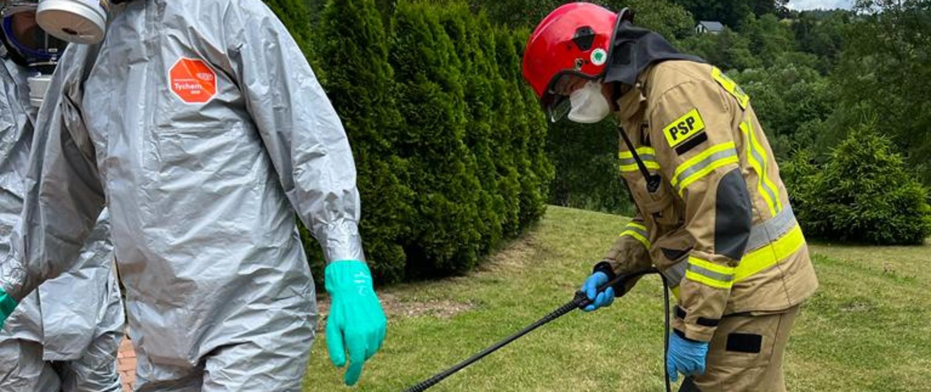 Strażacy w ubraniach ochronnych z opryskiwaczem