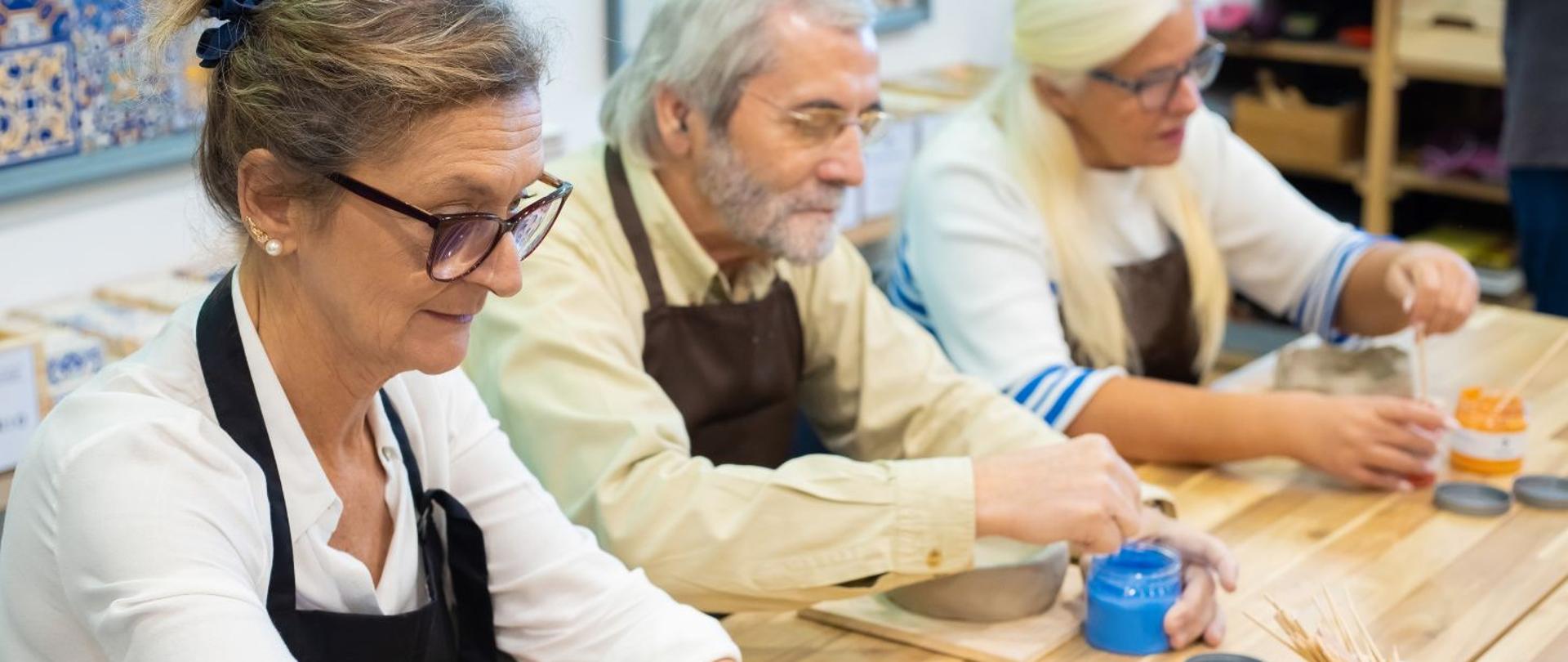 Trzy starsze osoby uczestniczące w zajęciach plastycznych