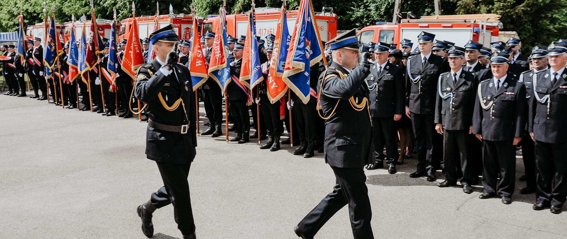 następuje przegląd pododdziałów dowódca uroczystości starszy kapitan Erwin Mospinek oraz zastępca komendanta wojewódzkiego w łodzi starszy brygadier sebastian kościsty przechodzą przed sztandarami wszystkich OSP w powiecie brzezińskim oraz pododdziałami salutując, 