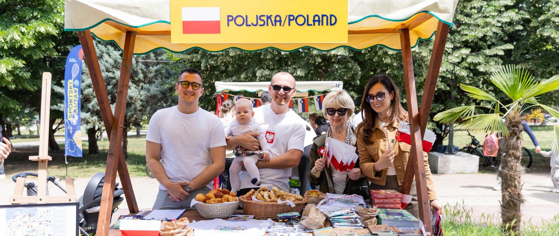 Poljski štand sa suvenirima; predstavnici Ambasade i Udruženja Poljaka za štandom sa zastavicama Poljske