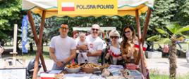Poljski štand sa suvenirima; predstavnici Ambasade i Udruženja Poljaka za štandom sa zastavicama Poljske