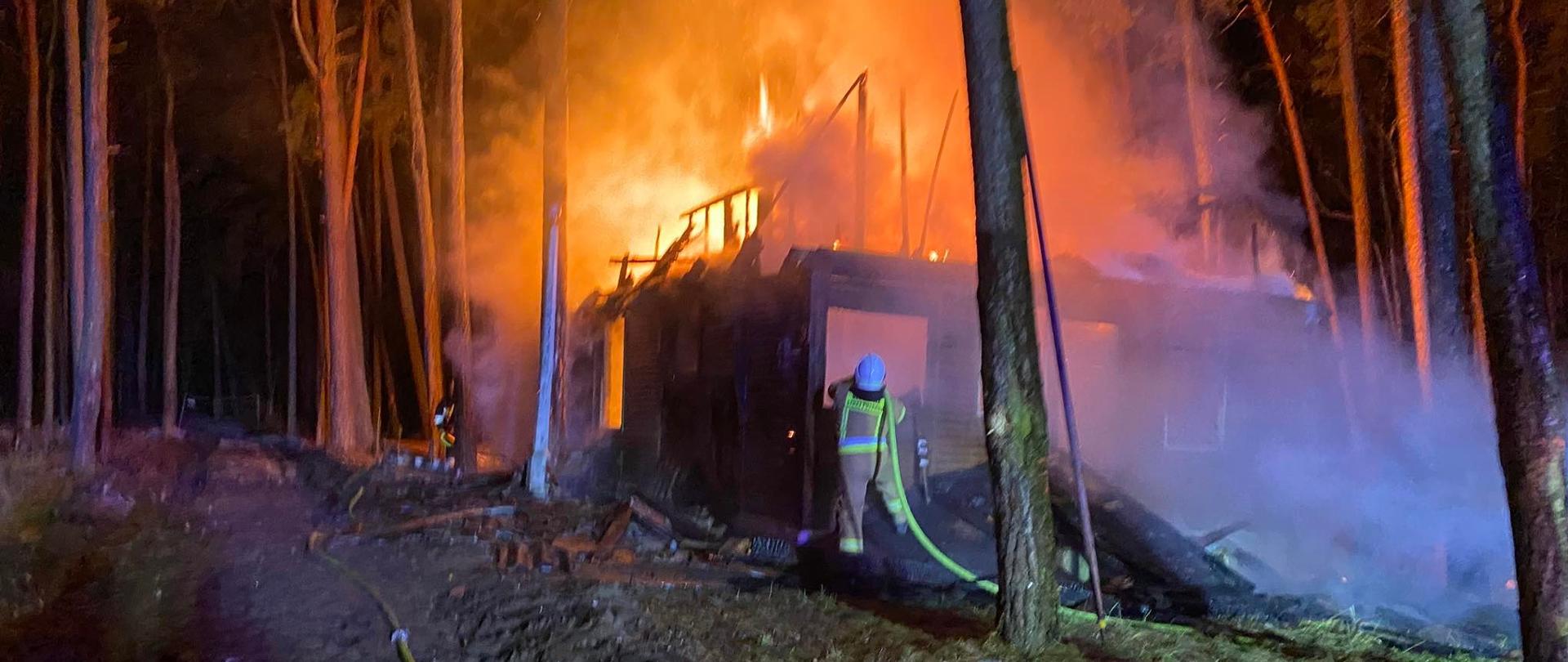 Akcja gaśnicza drewnianego domku. Strażak podczas działań gaśniczych