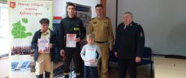 Na zdjęciu troje uczestników dumnie pokazuje swoje dyplomy, obok nich znajduje się Komendant Miejski i Druh Prezes Związku Ochotniczej Straży Pożarnej. 