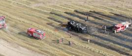 Ujęcie z drona. Spalony ciągnik i prasa do słomy. Strażacy gaszą maszyny rolnicze.