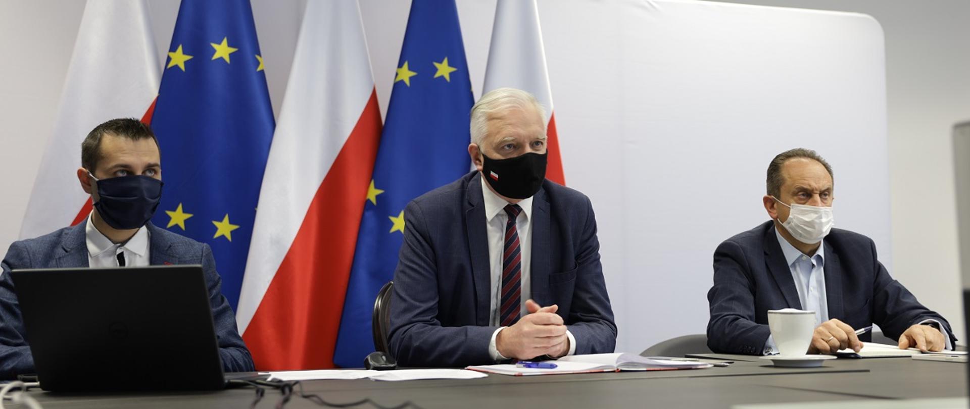 Wicepremier J. Gowin siedzący za stołem w maseczce, po prawej wiceminister rozwoju, pracy i technologii Andrzej Gut-Mostowy.