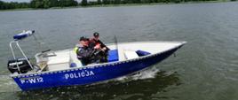 Zdjęcie przedstawia policjanta i strażaka w łodzi policyjnej podczas patrolu na jeziorze Raduń
