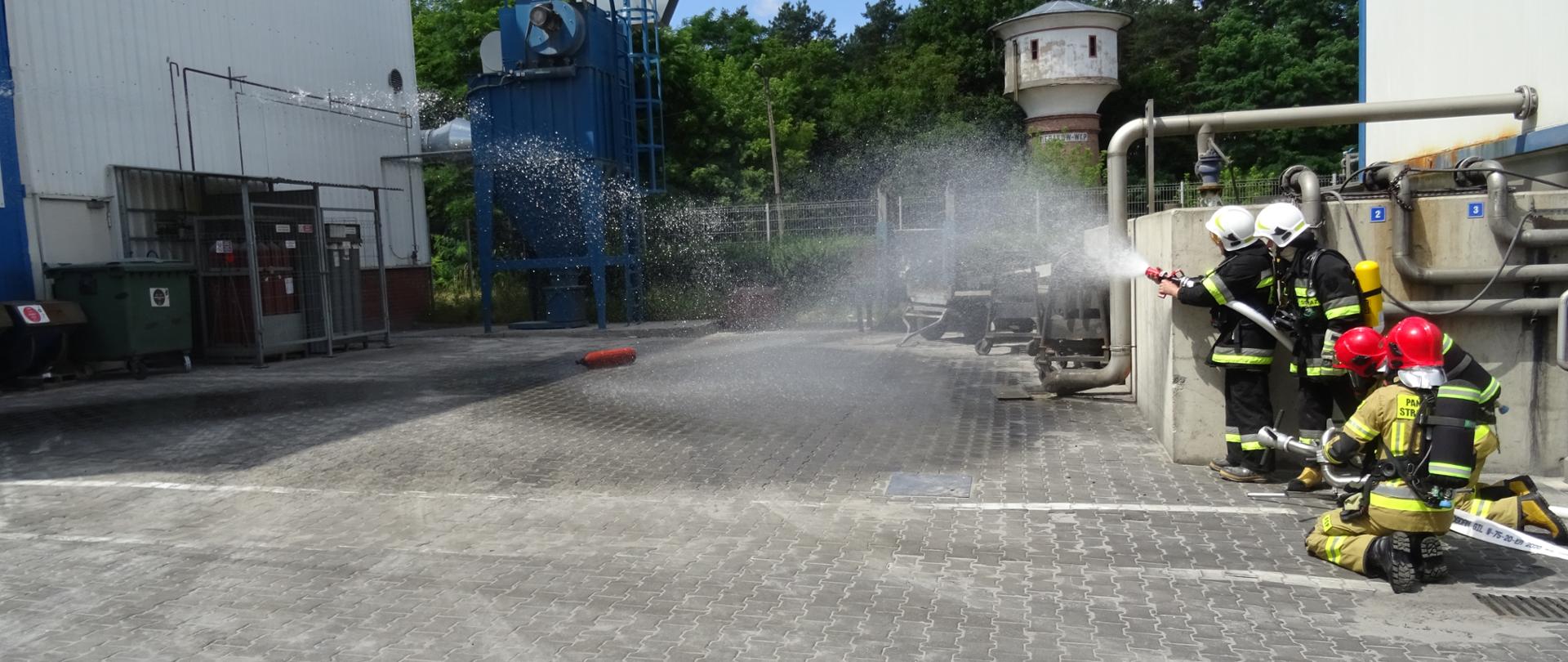 Strażacy chłodzą butlę z acetylenem.