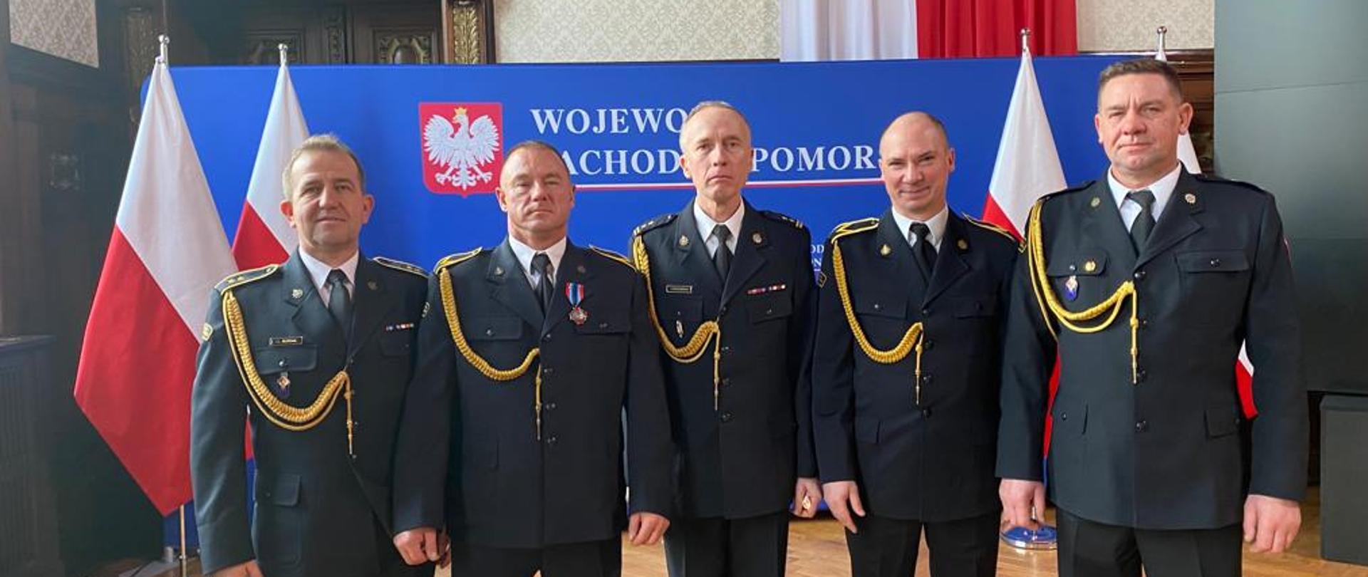 Zdjęcie przedstawia 5 mężczyzn ubranych w mundury wyjściowe na Uroczystości wręczenia odznaczeń, wyróżnień dla funkcjonariuszy PSP oraz Korpusu Służby Cywilnej