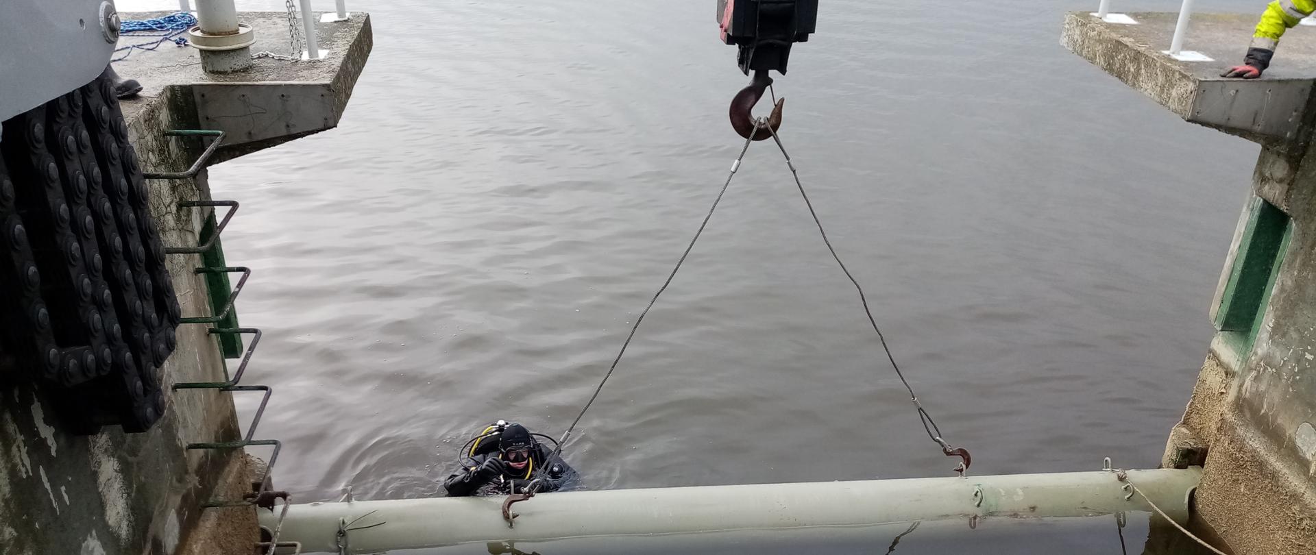 Rura spuszczana z zapory czołowej usytuowana jest nad taflą wody. Asekuruje ją znajdujący się w wodzie zbiornika płetwonurek.