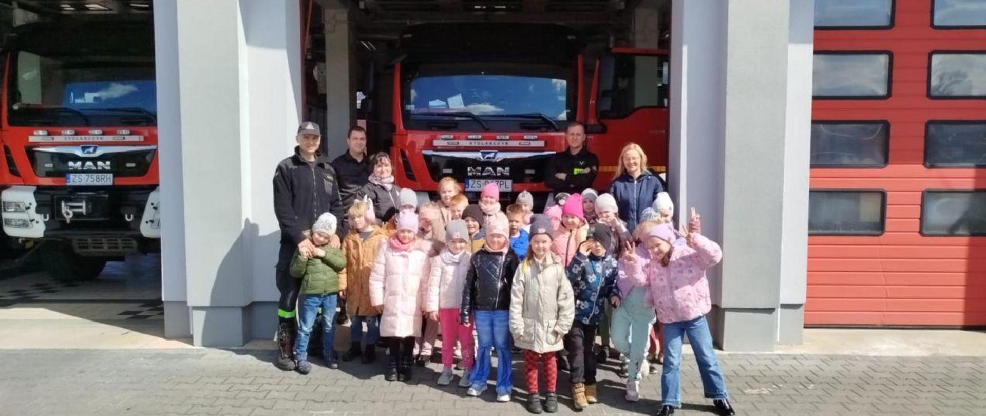 Na zdjęciu dzieci oraz strażak demonstrujący strażacki sprzęt.