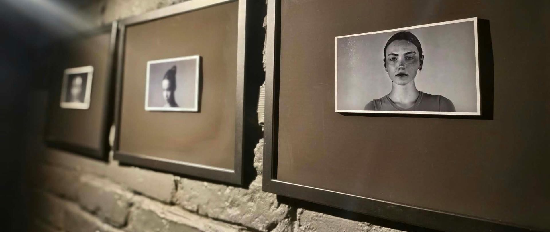 Fragment wystawy przedstawiający portrety kobiet wyeksponowane na ceglastym murze