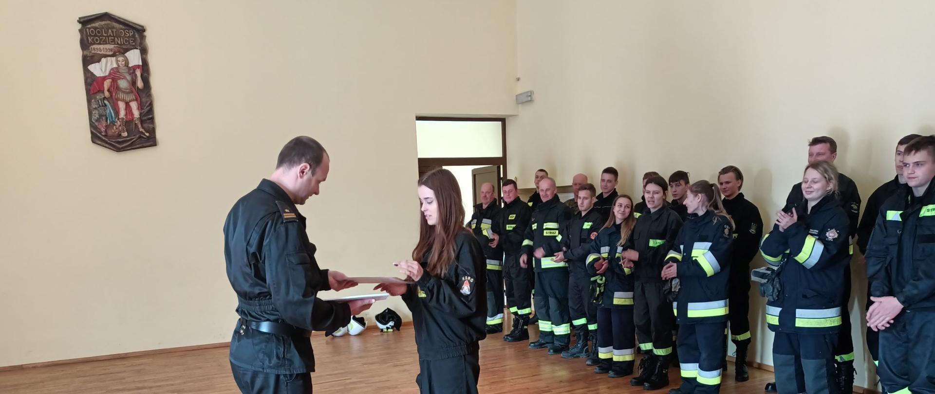 Zastępca komendanta powiatowego PSP w Kozienicach wręcza zaświadczenie o ukończeniu szkolenia.