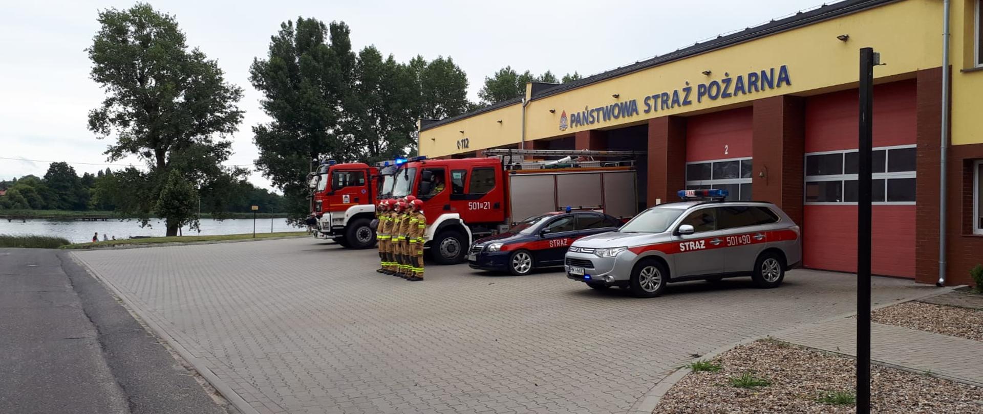 Zdjęcie przedstawia międzychodzkich strażaków stojących przez pojazdami pożarniczymi podczas godziny "W" - 17:00.