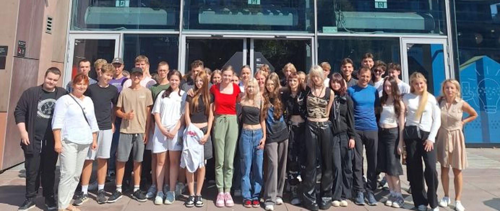 Grupa uczestników stoi przed budynkiem Centrum Nauki Kopernik