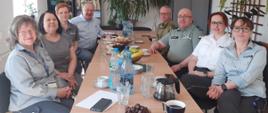 osiem osób siedzi po obu stronach stołu, wszyscy są w mundurach różnych służb granicznych