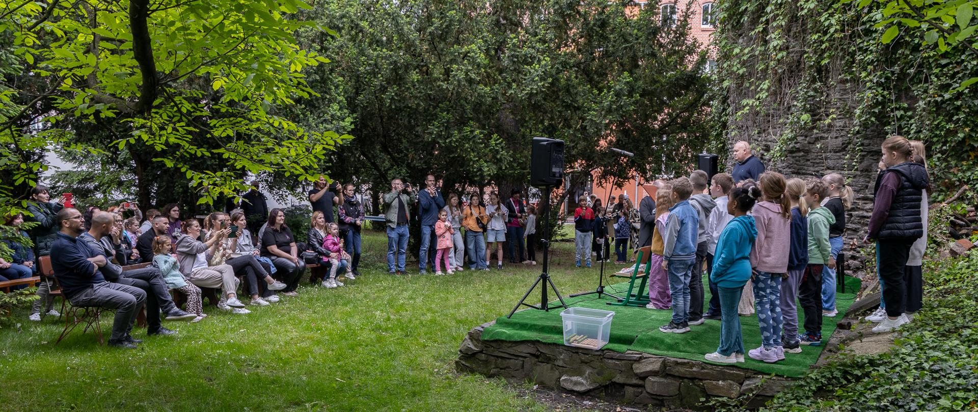 dzieci występujące podczas pikniku oraz słuchająca ich publiczność