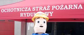Strażak w przebraniu strażaka sama na tle jednostki ratowniczo0gaśniczej w Rydułtowach