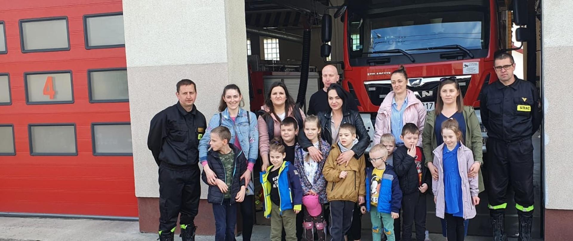 Grupowe zdjęcie dzieci wraz z opiekunami i strażakami przed samochodem gaśniczym w KP PSP w Żurominie.