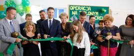 Uczniowie i dorośli przecinają wstęgę.