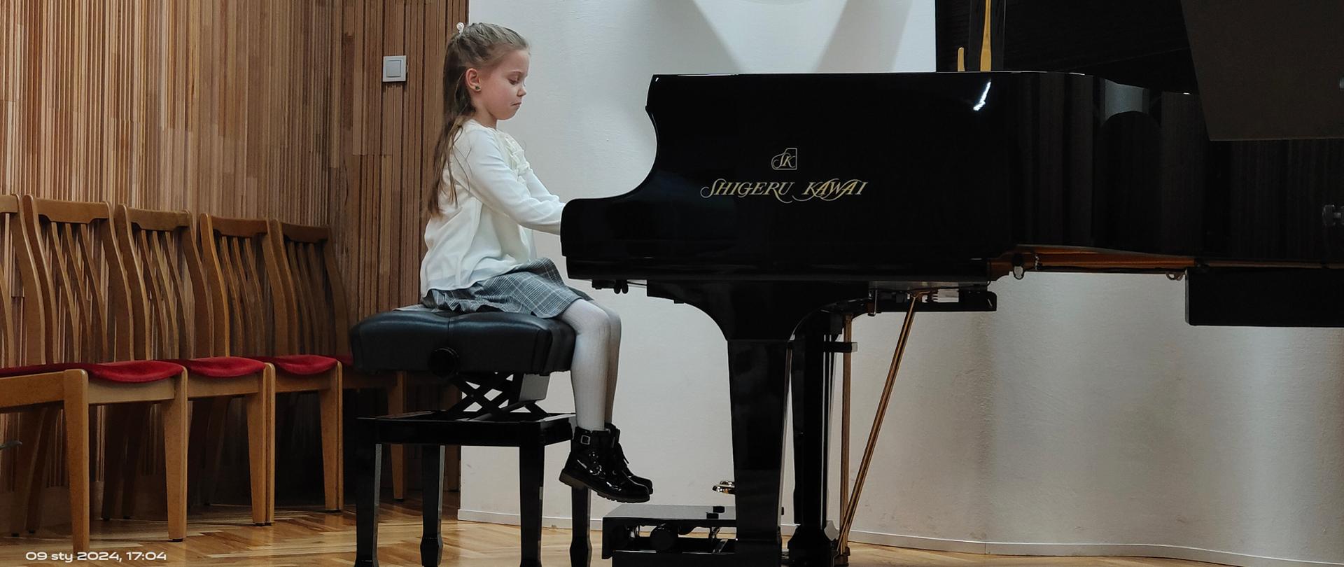 Uczennica gra na fortepianie podczas występu na scenie