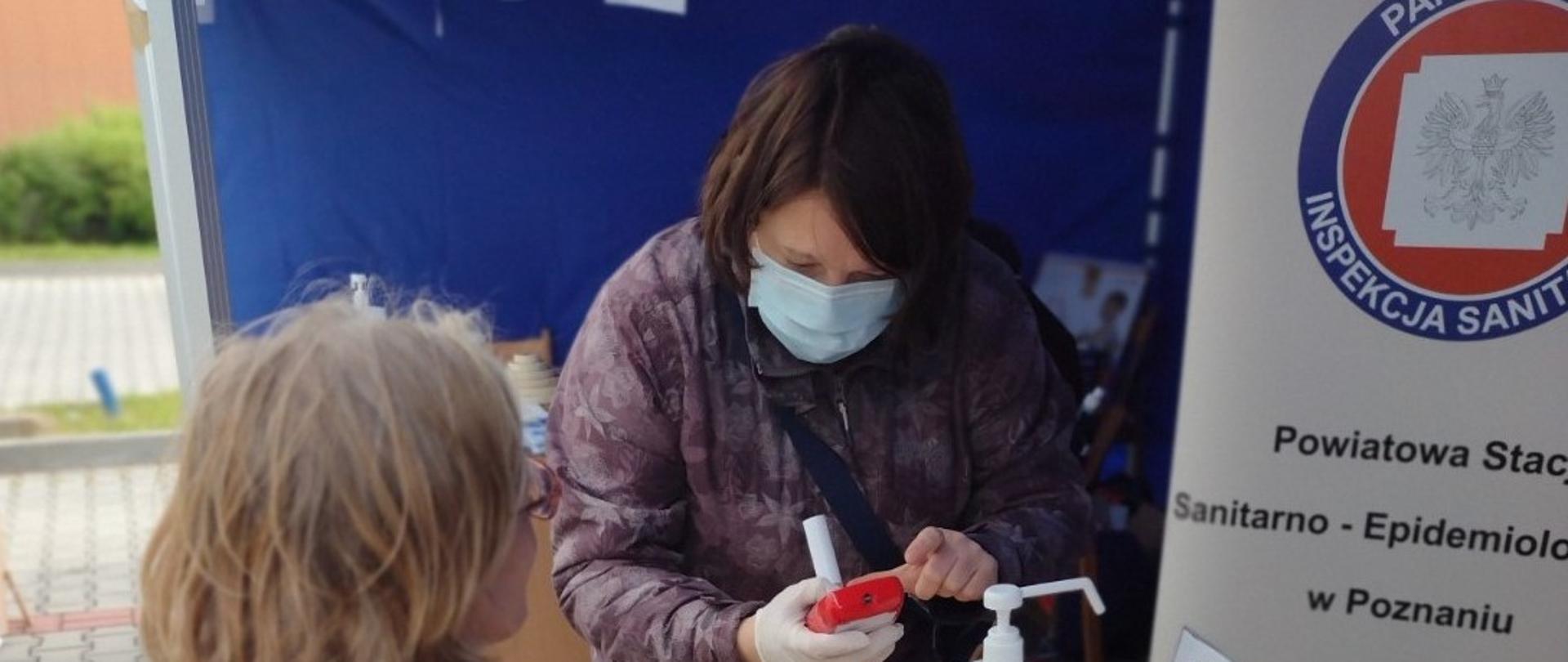 po lewej stronie pracownica PSSE w Poznaniu przygotowuje się do pomiaru CO przy użyciu smokerlyzera