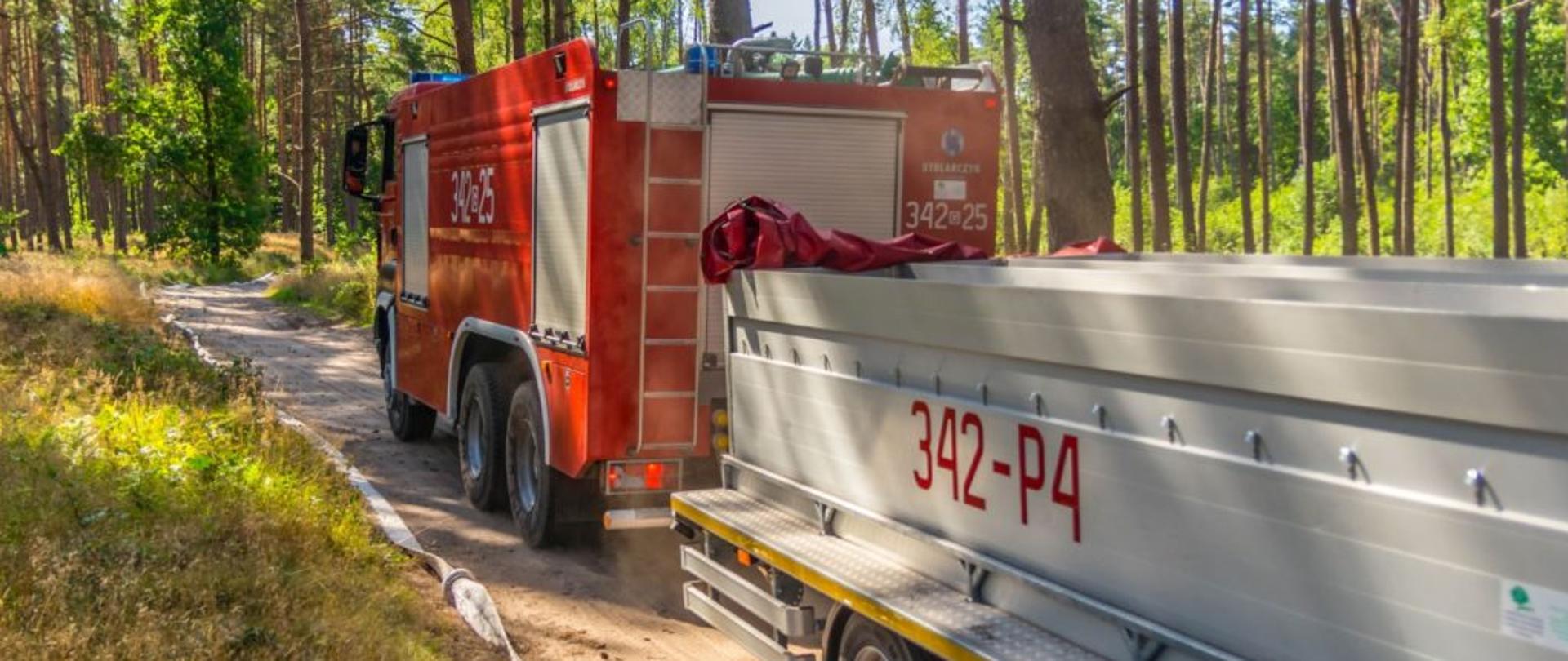 Zdjęcie ciężkiego samochodu gaśniczego wraz z przyczepą wężową uczestnicząca w ćwiczeniach. 