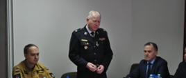 W sali konferencyjnej KP PSP w Ostrowcu Św. siedzą przy stolikach zaproszeni goście oraz strażacy. Na głównym planie stoi i przemawia Prezes Zarządu Powiatowego OSP druh Krzysztof Gajewski