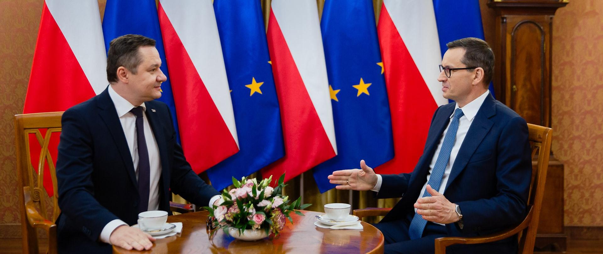Premier oraz Jakub Kiwior siedzą przy stole.