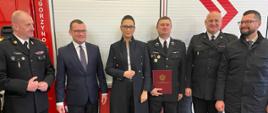 Zdjęcie przedstawia od lewej nadbryg. Jarosława Tomczyka, dh Jacka Skotnickiego, pana Pawła Szefernakera, Panią Małgorzatę Golińską, st. bryg. Dariusza Lubianiec, Marka Subocza na tle samochodu pożarniczegow trakcie wręczenia decyzji dotyczącej zakupu samochodu ratowniczo-gaśniczego dla jednostki OSP Człopa