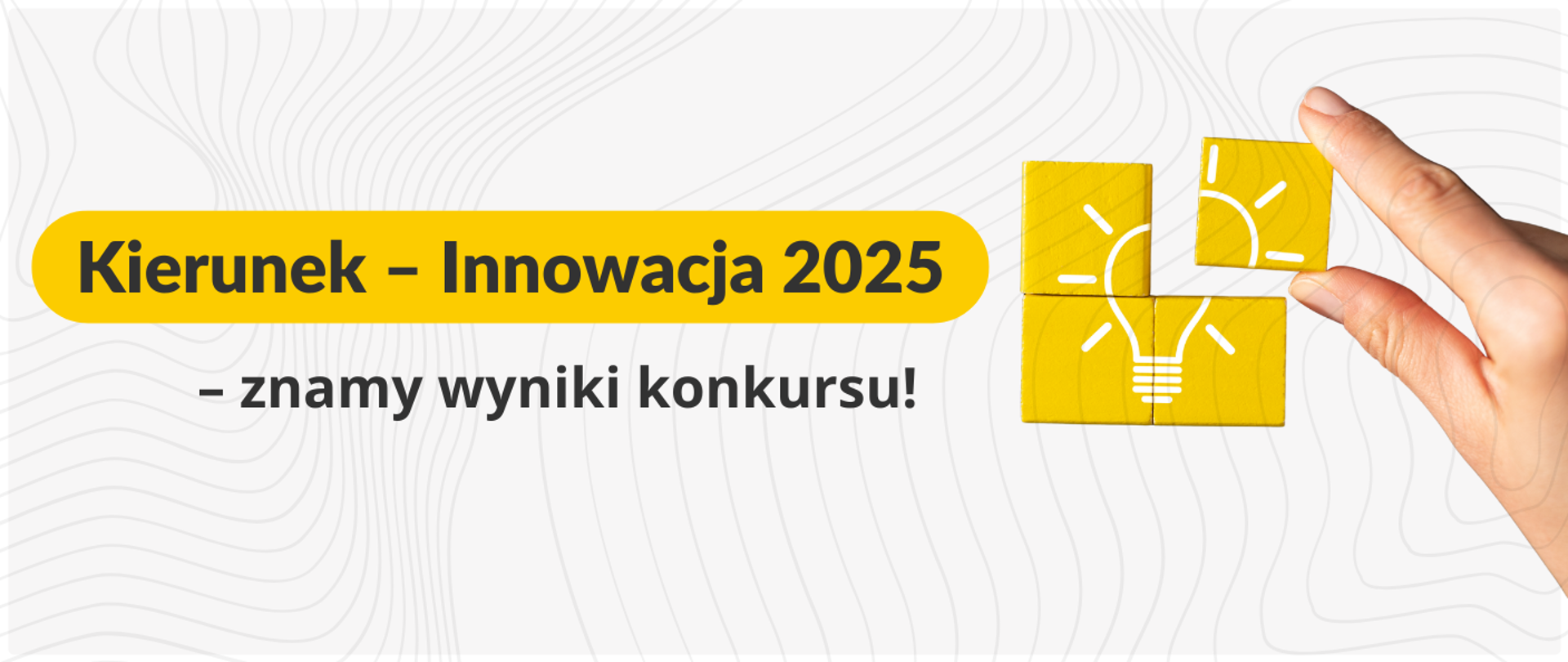 Grafika promocyjna z tłem w odcieniach szarości z abstrakcyjnym wzorem. Po lewej stronie znajduje się żółty baner z tekstem: "Kierunek – Innowacja 2025 – znamy wyniki konkursu!". Po prawej stronie ręka układa żółte, drewniane klocki, które razem tworzą symbol żarówki (ikony innowacji i pomysłu).