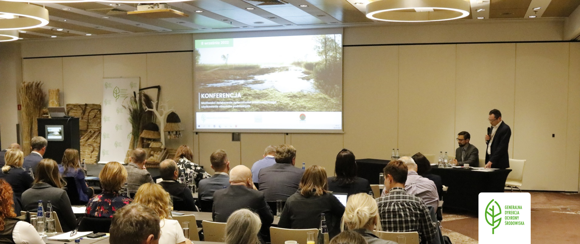 Przemawia Marek Kajs - Zastępca Generalnego Dyrektora Ochrony Środowiska. W sali konferencyjnej siedzą przedstawiciele instytucji związanych z gospodarowaniem rolniczym, gospodarowaniem zasobami wodnymi, ochroną przyrody oraz alternatywnym wykorzystaniem biomasy. 