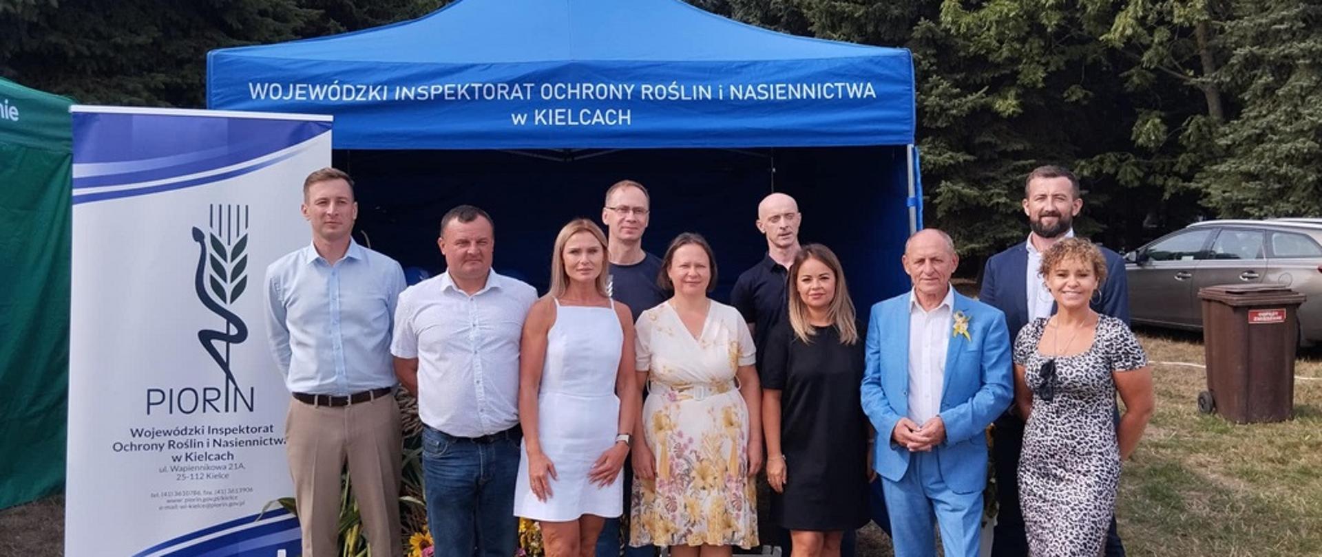 1. Pracownicy Wojewódzkiego Inspektoratu Ochrony Roślin i Nasiennictwa w Kielcach z Oddziałów w Sandomierzu i Opatowie wraz z Zastępcą Świętokrzyskiego Wojewódzkiego Inspektora Ochrony Roślin i Nasiennictwa Panem Zenonem Piecabą stoją przed granatowym namiotem na Powiatowym Święcie Plonów w Sandomierzu. 