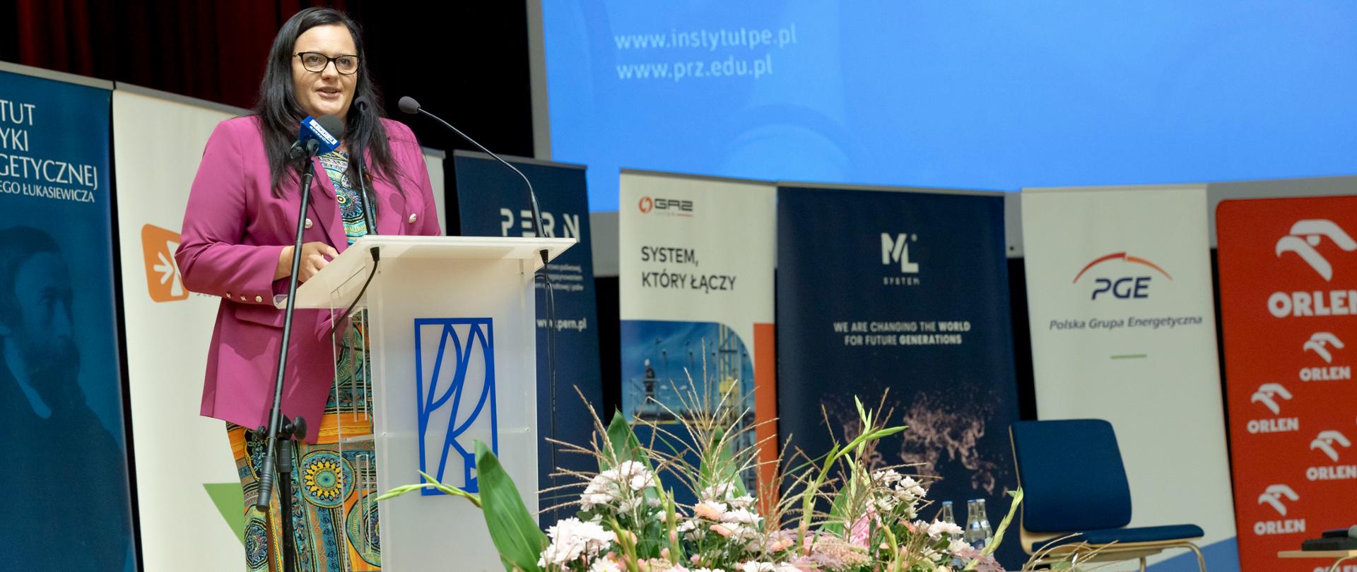 Wiceminister Małgorzata Jarosińska-Jedynak w mównicy na tle banerów