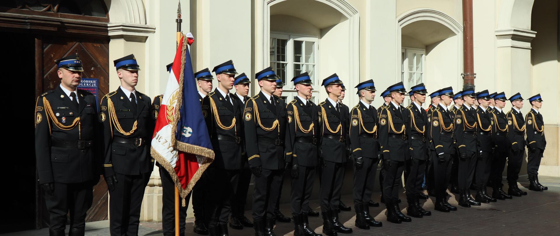 Stojąca w dwuszeregu kompania honorowa Centralnej Szkoły PSP w raz z pocztem sztandarowym oraz dowódcą