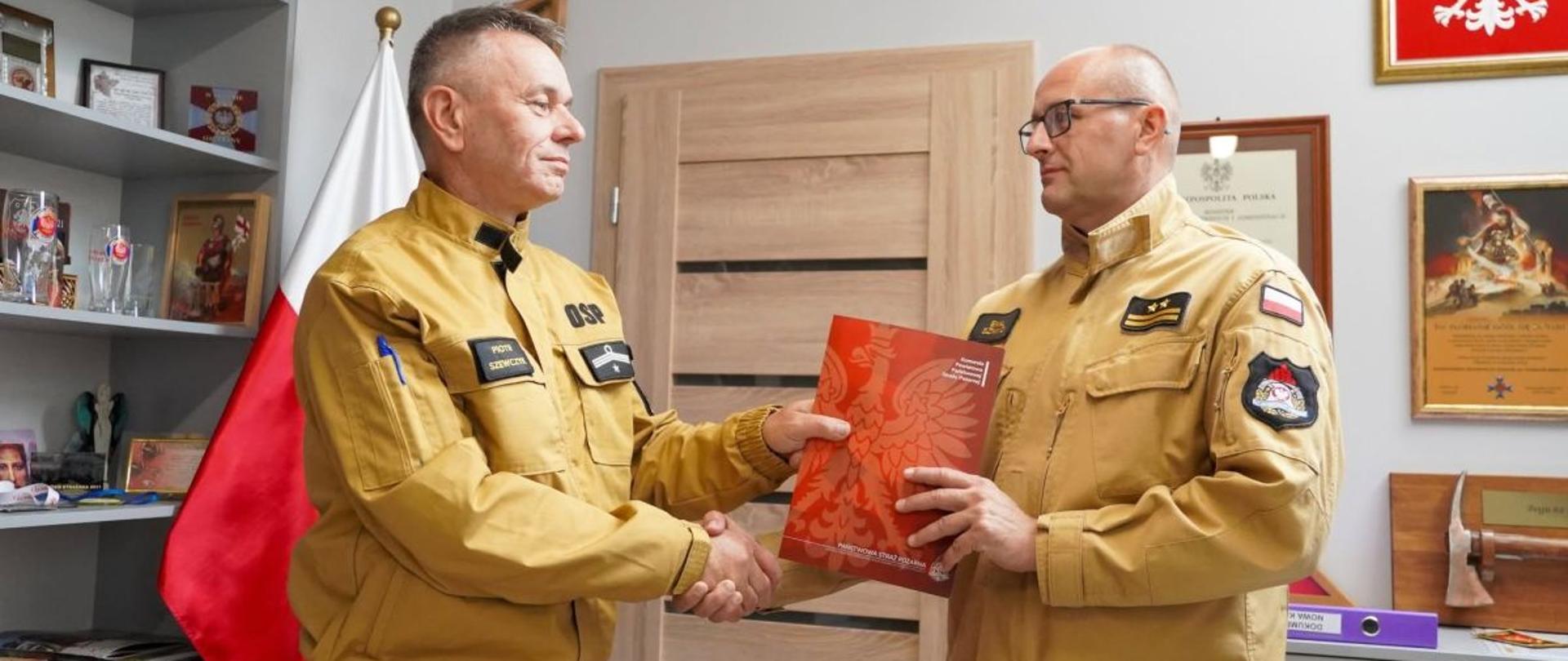 Zdjęcie przedstawia komendanta powiatowego który przekazuje prezesowi OSP Krościenko decyzję o przekazaniu skutera śnieżnego. 