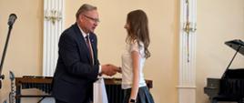 Poseł Andrzej Gawron oraz nagrodzony uczeń na scenie w sali koncertowej podczas Uroczystego Koncertu Absolwentów w Państwowej Szkole Muzycznej I st. w Lublińcu