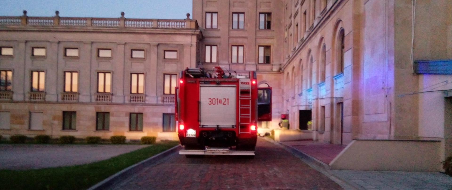 Zdjęcie przedstawia budynki Uniwersytetu Jana Kochanowskiego w Kielcach przy ulicy Stefana Żeromskiego. Na podjeździe stoi samochód gaśniczy.