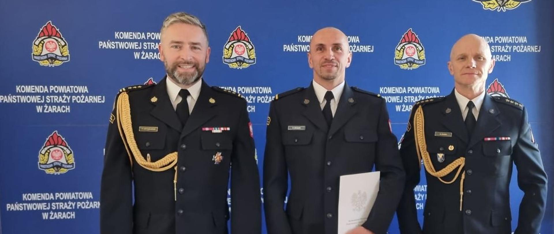 Na zdjęciu widoczny jest strażak mianowany do służby stałej w obecności Komendanta Powiatowego i Dowódcy JRG