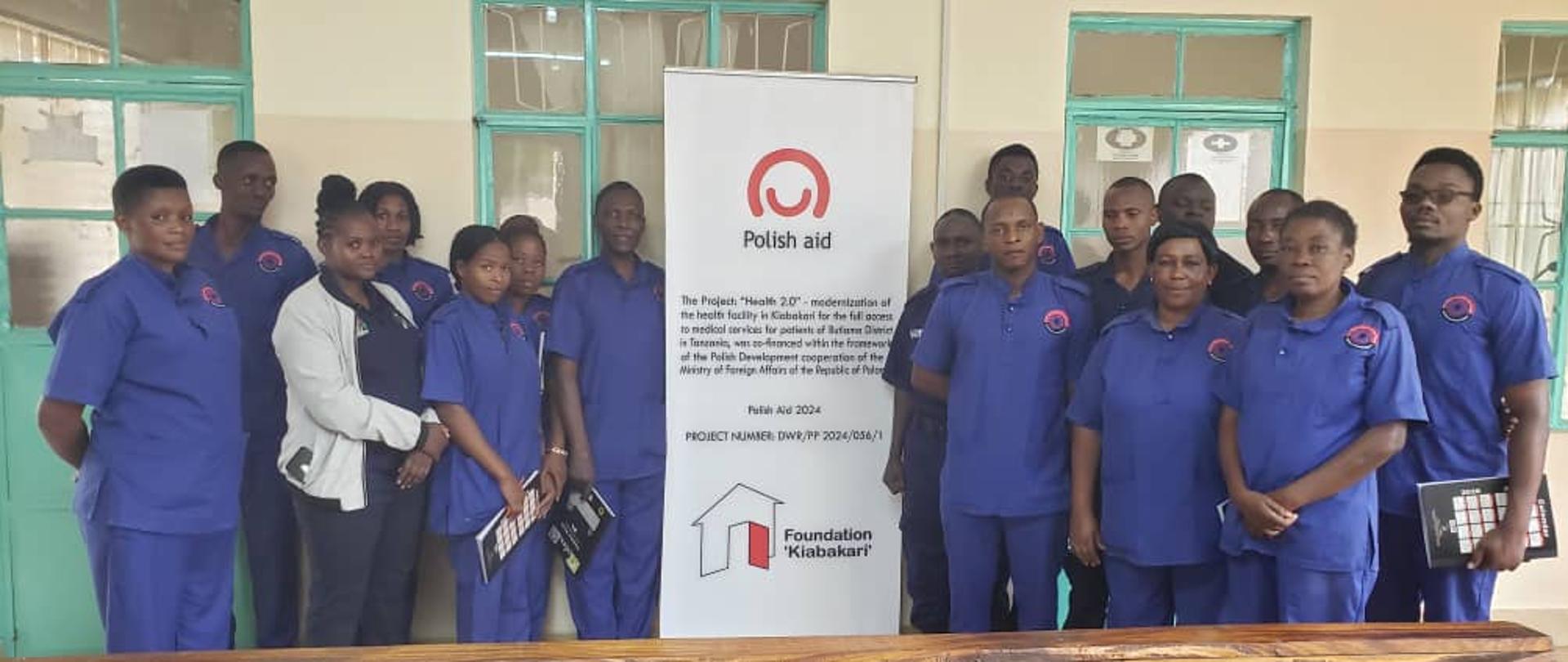 Grupa osób pozuje do zdjęcia przed kliniką, są ubrani w stroje pracowników medyczynych