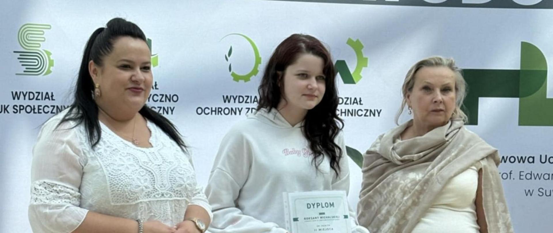 Uczennica z dyplomem w towarzystwie dwóch kobiet - członków jury konkursowego