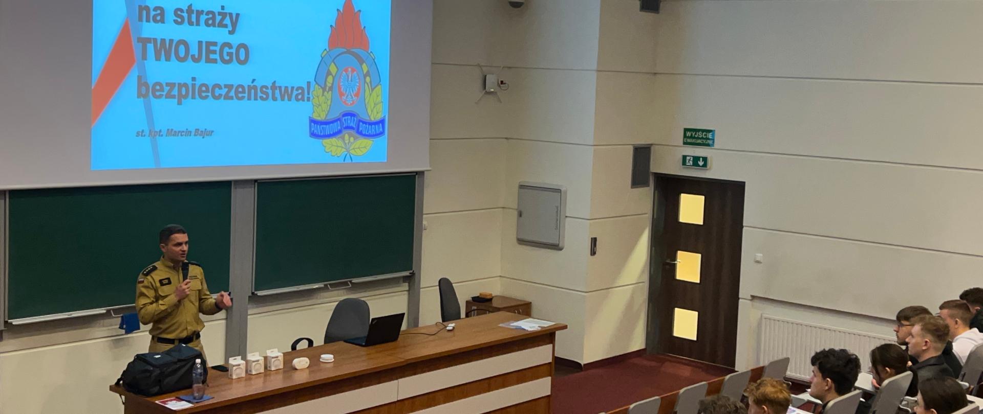 W auli siedzą studenci a wykład prowadzi strażak
