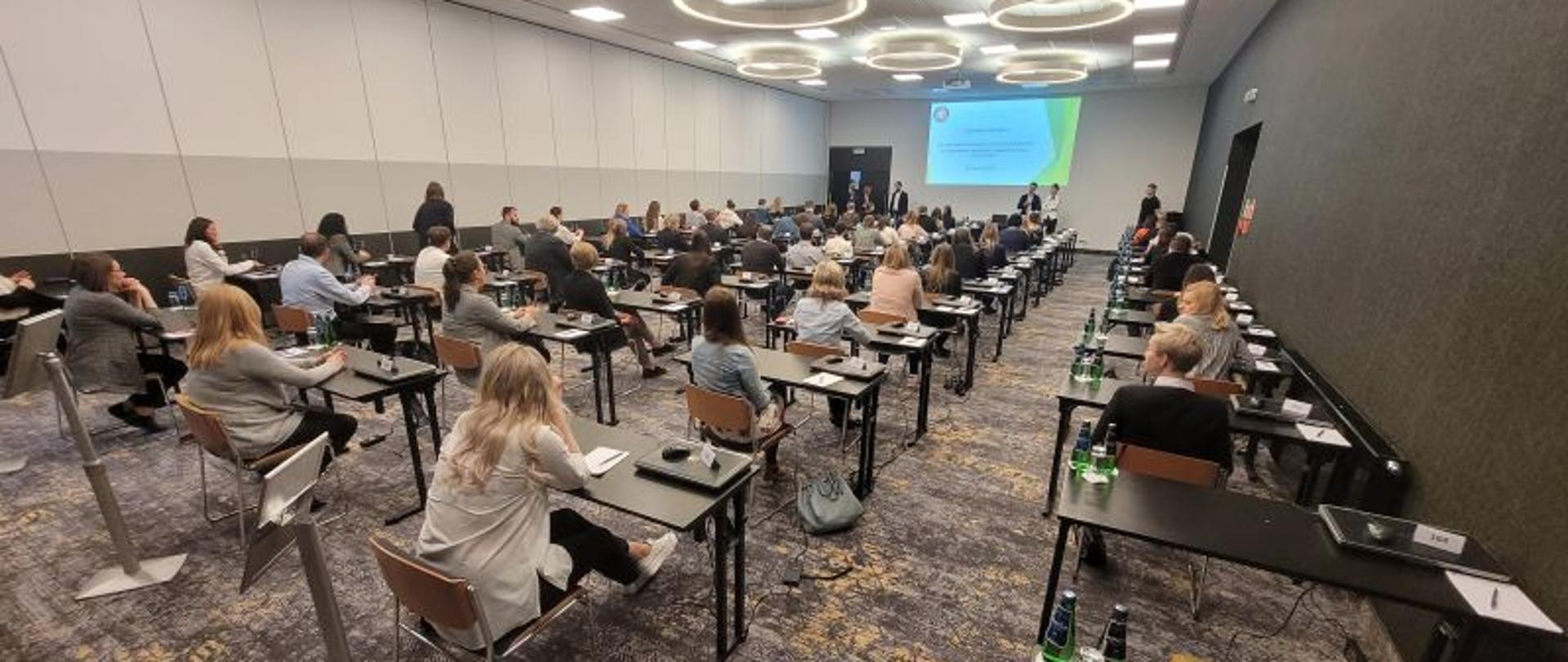 Kandydaci na inspektora ochrony środowiska siedzą w ławkach i czekają na rozpoczęcie egzaminu