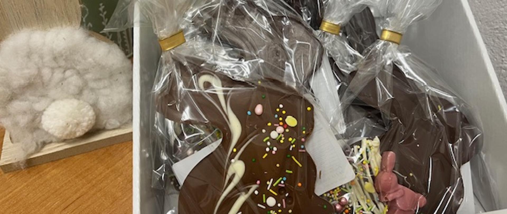Czekoladowe zajączki wielkanocne owinięte w kolorową folię, ustawione obok siebie jako świąteczne słodycze i dekoracje.