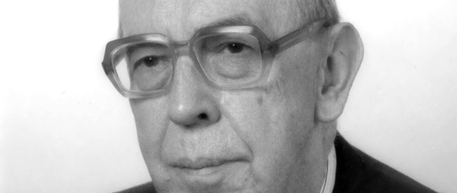 Krzysztof Skubiszewski czarno-biały portret mężczyzny w okularach z grubymi oprawkami, siwe włosy, ciemna marynarka, ciemny krawat, biała koszula w paski.