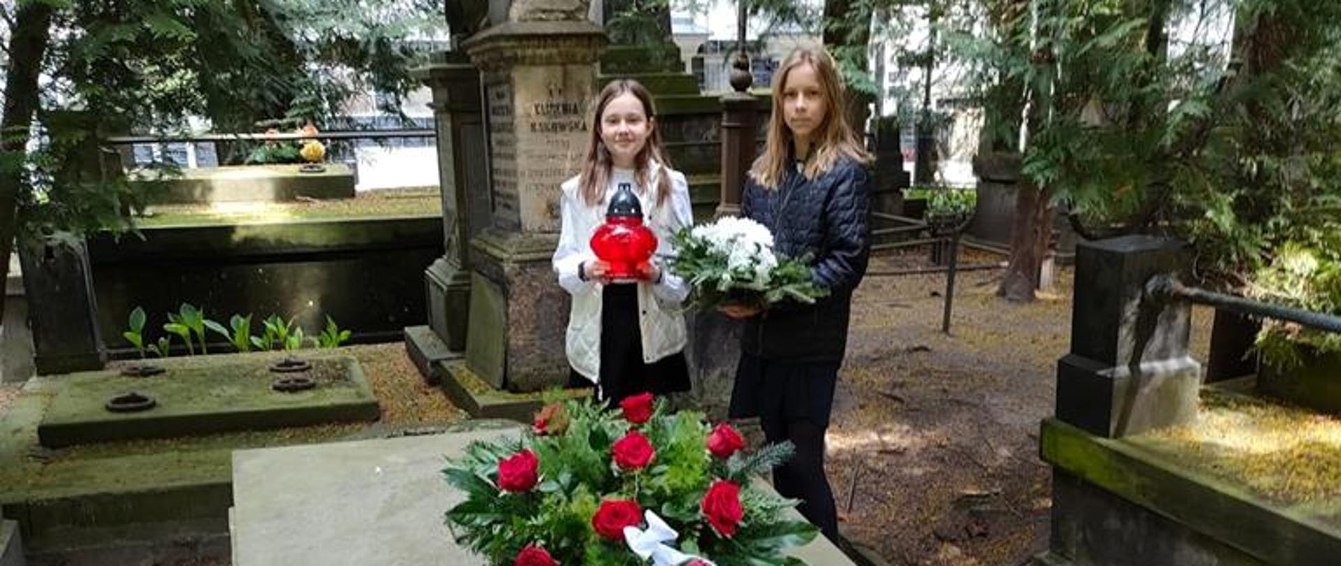 Na środku zdjęcia widać 2 uczennice składające kwiaty na grobie Stanisława Moniuszki