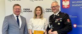 grupa oficjeli, w tym wojewoda, pozują do zdjęcia na tle ścianki 