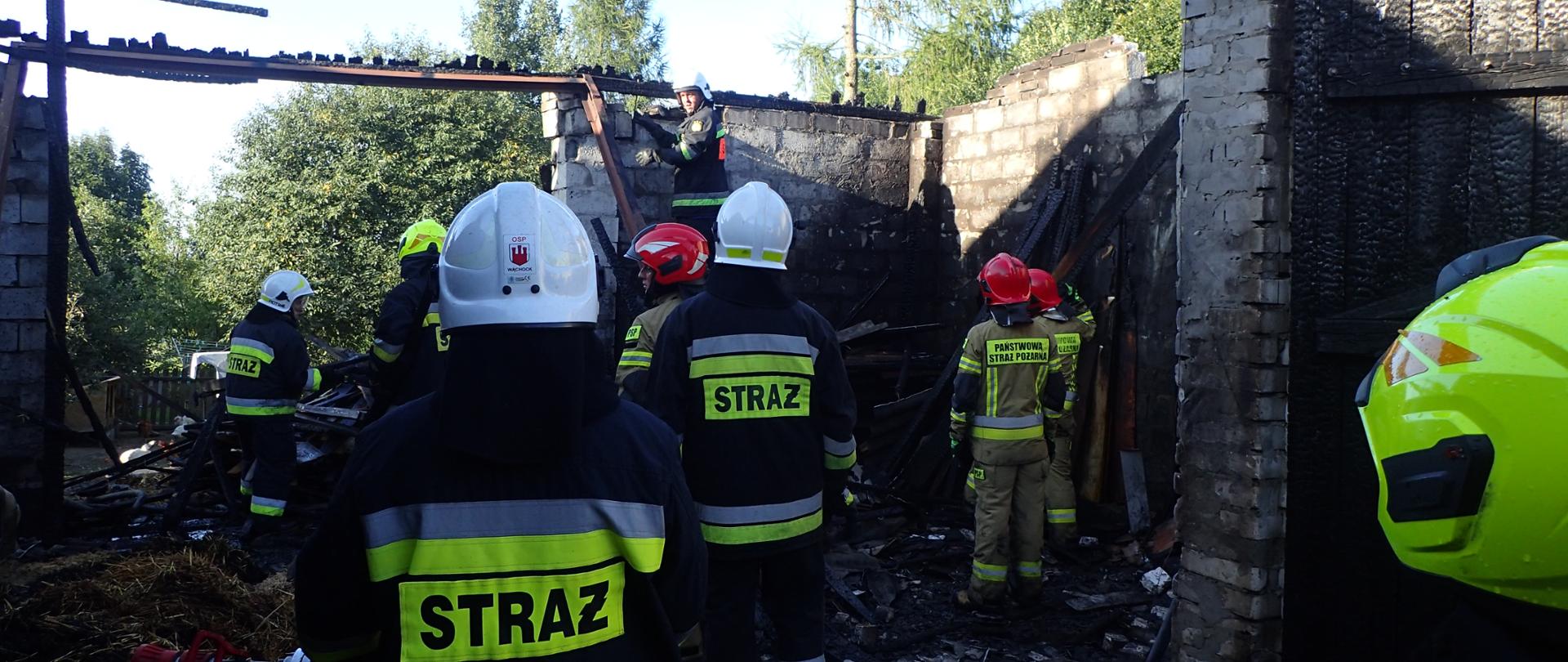 Zdjęcie przedstawia wnętrze spalonego budynku oraz biorących udział w akcji funkcjonariuszy PSP i OSP